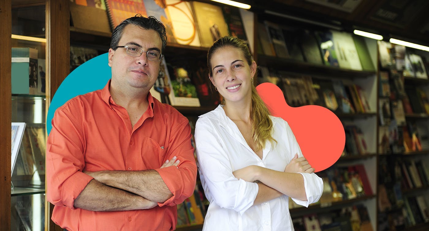 A man in a red shirt and a woman in a white shirt posing in front of book shelves
