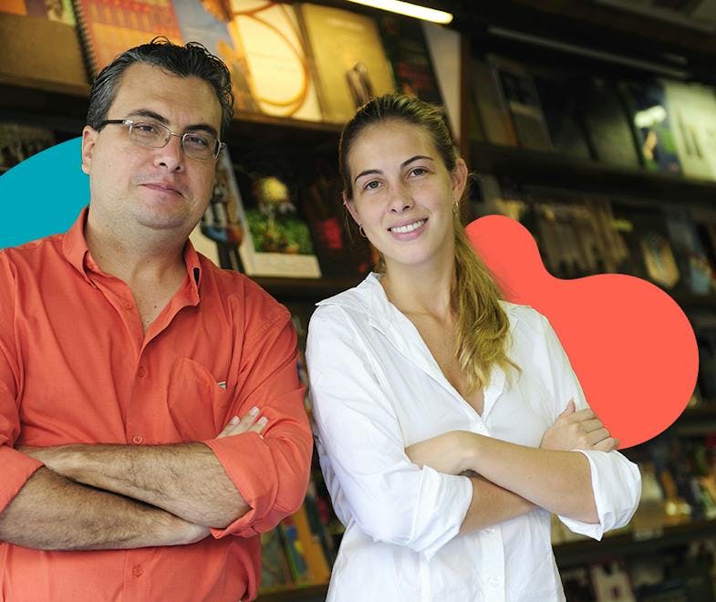 A man in a red shirt and a woman in a white shirt posing in front of book shelves