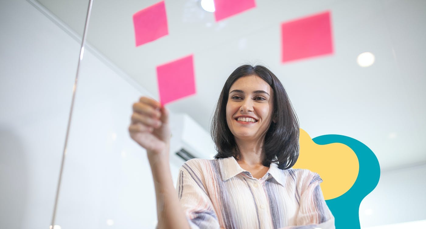 Female business owner fleshing out her news business with post it notes on a glass wall