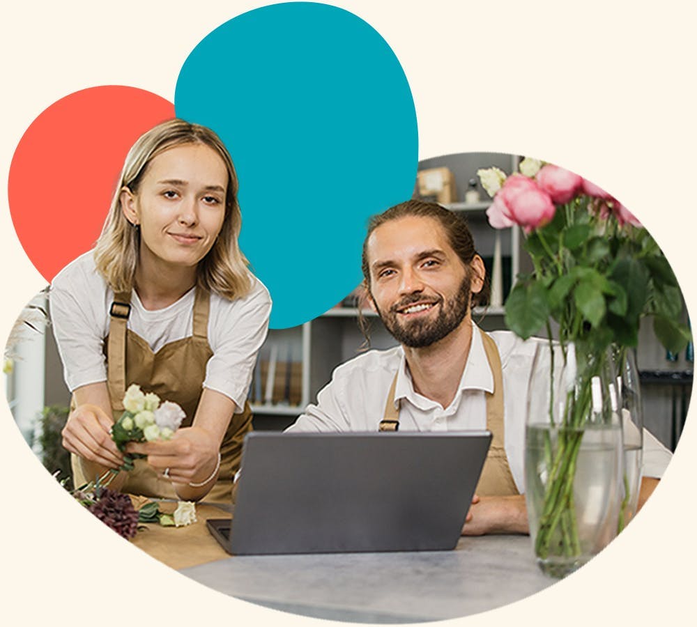 a man and a woman wearing aprons at a flower shop checking Xero file on their laptop